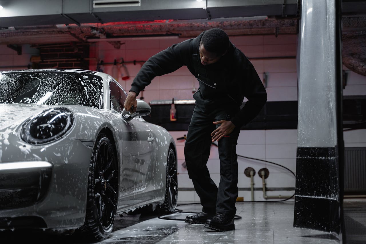 Desventajas del tratamiento cerámico: cuándo no deberías aplicarlo 4 Detailer lavando a mano con espuma un Porsche 911 plateado en una zona de lavado