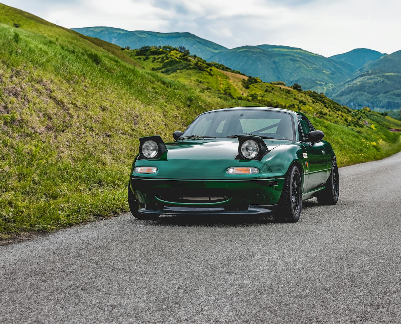 Desventajas del tratamiento cerámico: cuándo no deberías aplicarlo 3 Mazda MX-5 de primera generación verde con la pintura brillante en una carretera de montaña