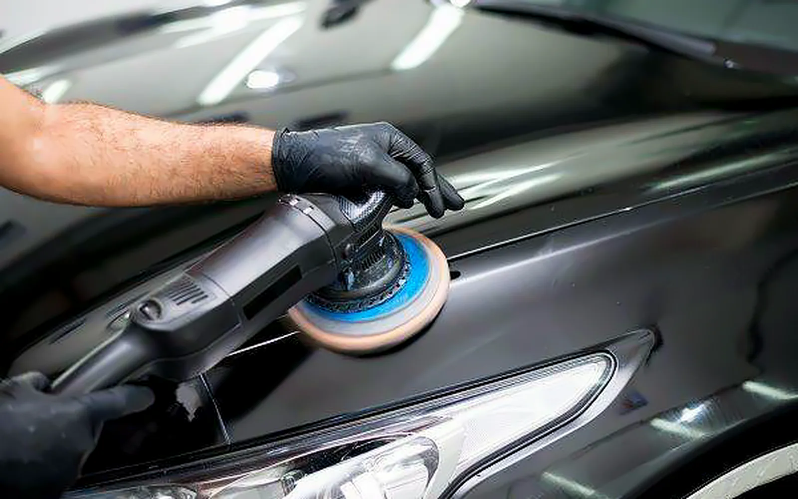 Ventajas del detailing: por qué compensa cuidar así tu coche 1 Detailer puliendo a máquina la aleta de un coche negro: ventajas del detailing en la pintura
