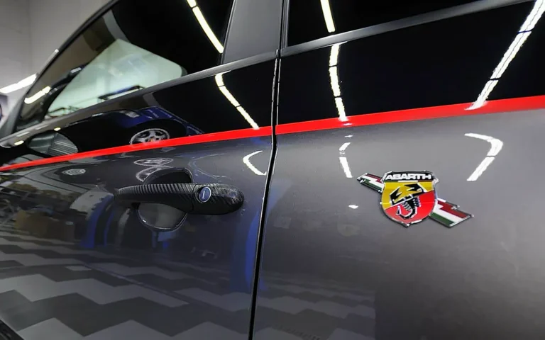 Puerta de un Abarth gris con franja roja y reflejos nítidos gracias al coating cerámico