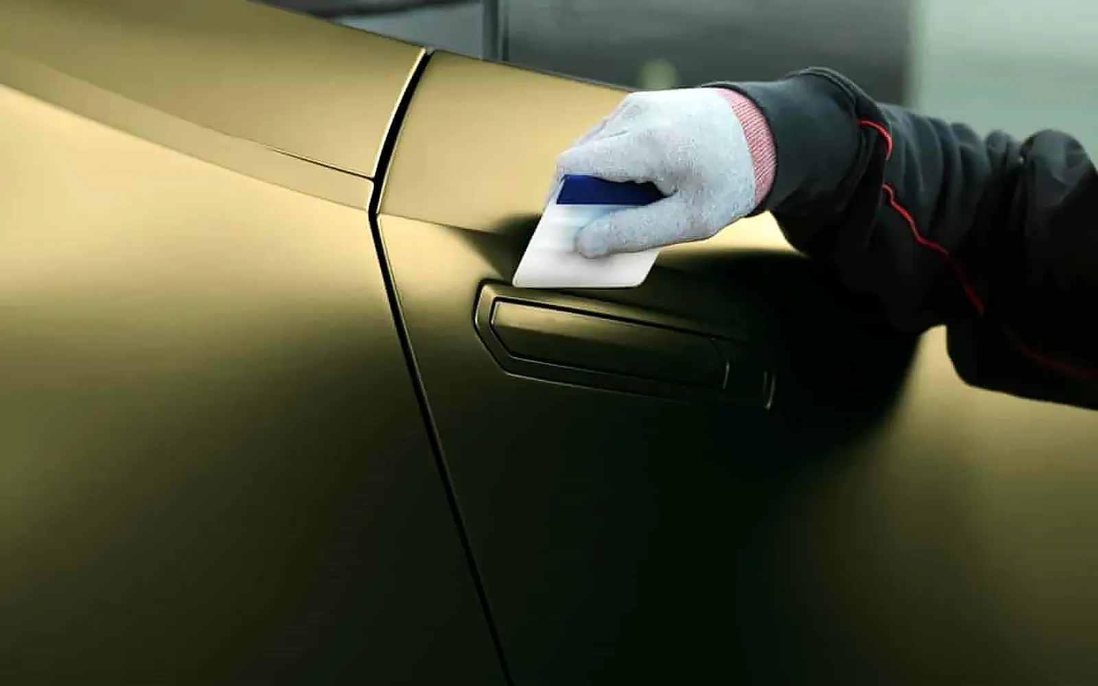Cuánto cuesta vinilar el techo de un coche y otras piezas 1 Espátula sobre vinilo verde oliva mate en una puerta, el mismo trabajo que vinilar el techo de un coche