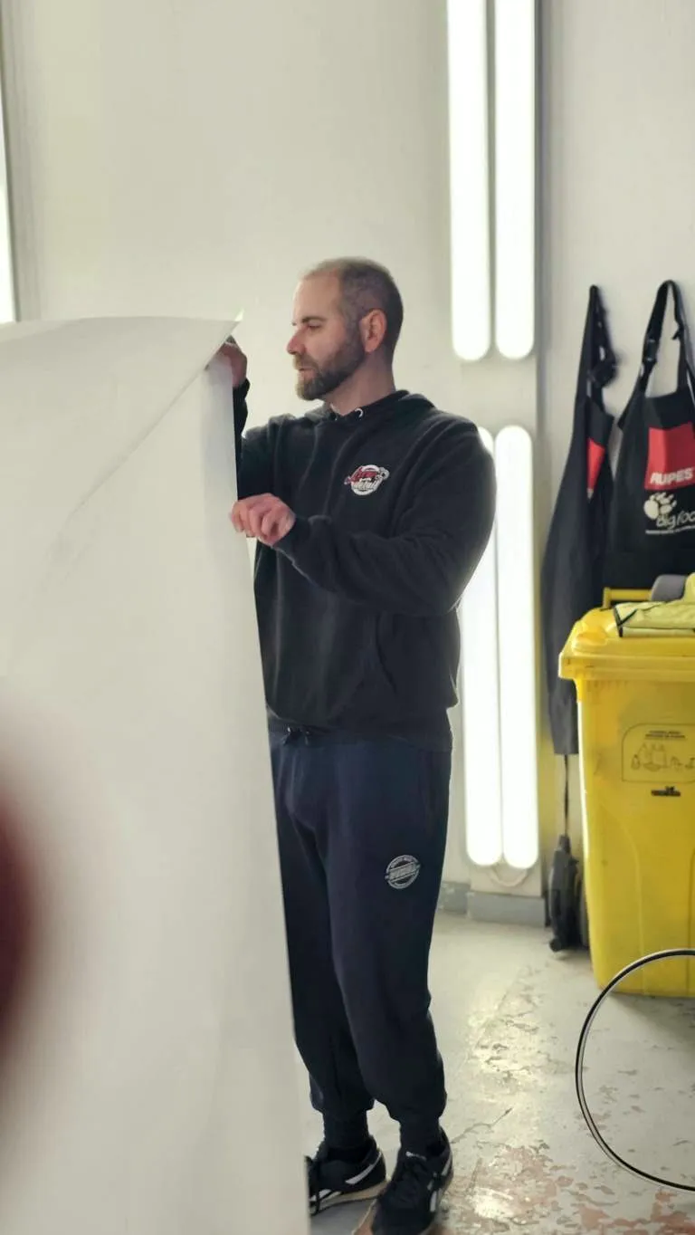 Cursos de Paint Protection Film 9 Alumno sujetando una lámina de PPF de gran formato en la cabina del taller
