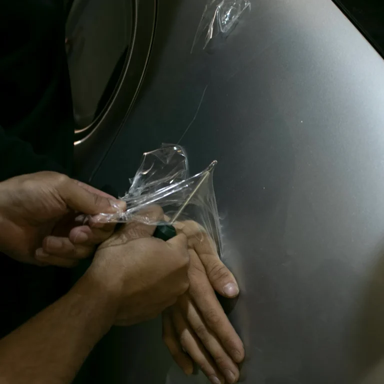 Cursos de Paint Protection Film 13 Manos estirando lámina de PPF transparente sobre la aleta de un coche plateado
