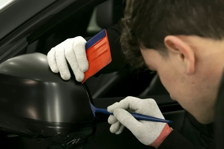 Curso de Car Wrapping 14 Alumno rematando con rasqueta y cuchilla el vinilo negro mate de un retrovisor