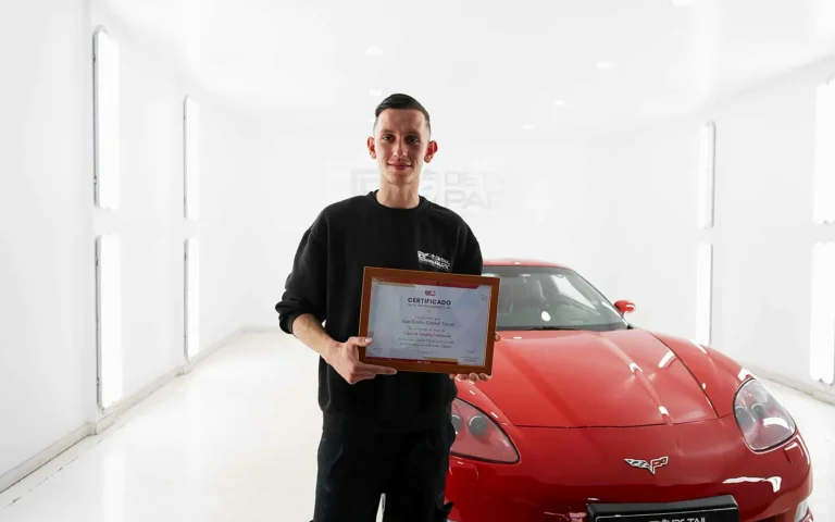 Juan Emilio con su certificado tras estudiar detailing en Detail Park, junto a un deportivo rojo