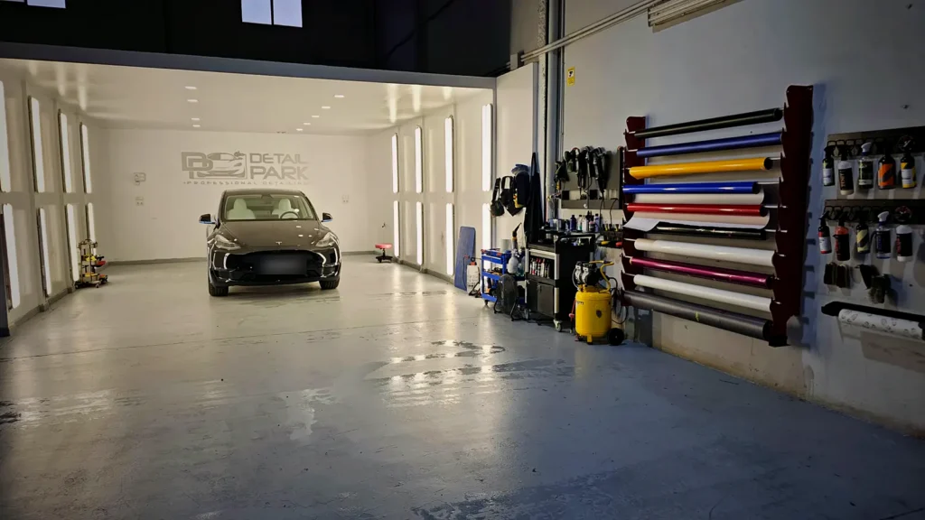 El Equipo 14 Cabina con iluminación de estudio con un Tesla dentro y un expositor de rollos de vinilo de colores en la pared
