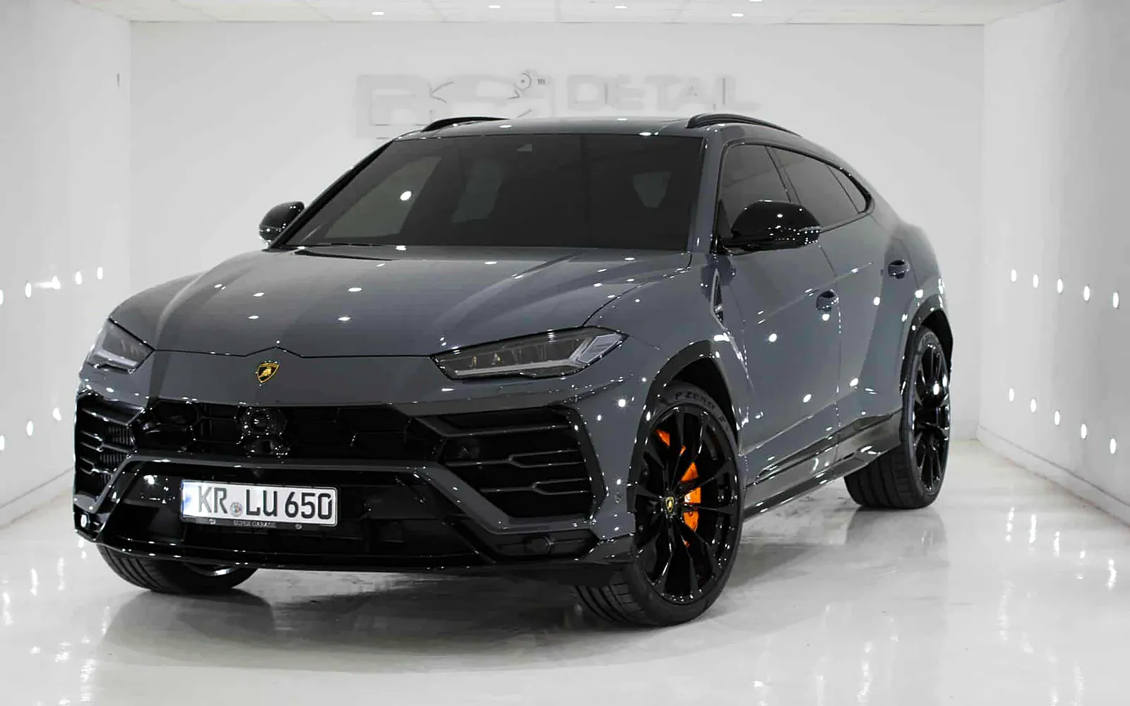 Detailing Lamborghini Urus: pulido profesional y cera de carnauba 1 Detailing Lamborghini Urus terminado: SUV gris con pinzas de freno naranjas en el estudio de luz
