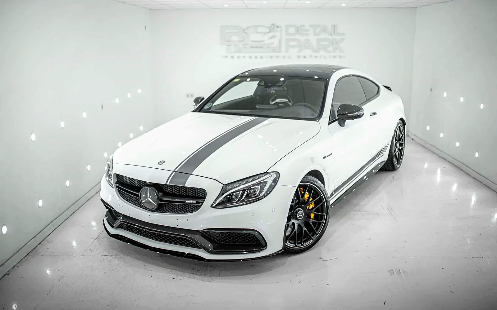 PPF Mercedes C63: detailing completo y frontal protegido 1 PPF Mercedes C63: coupé blanco en tres cuartos delantero con la franja de vinilo