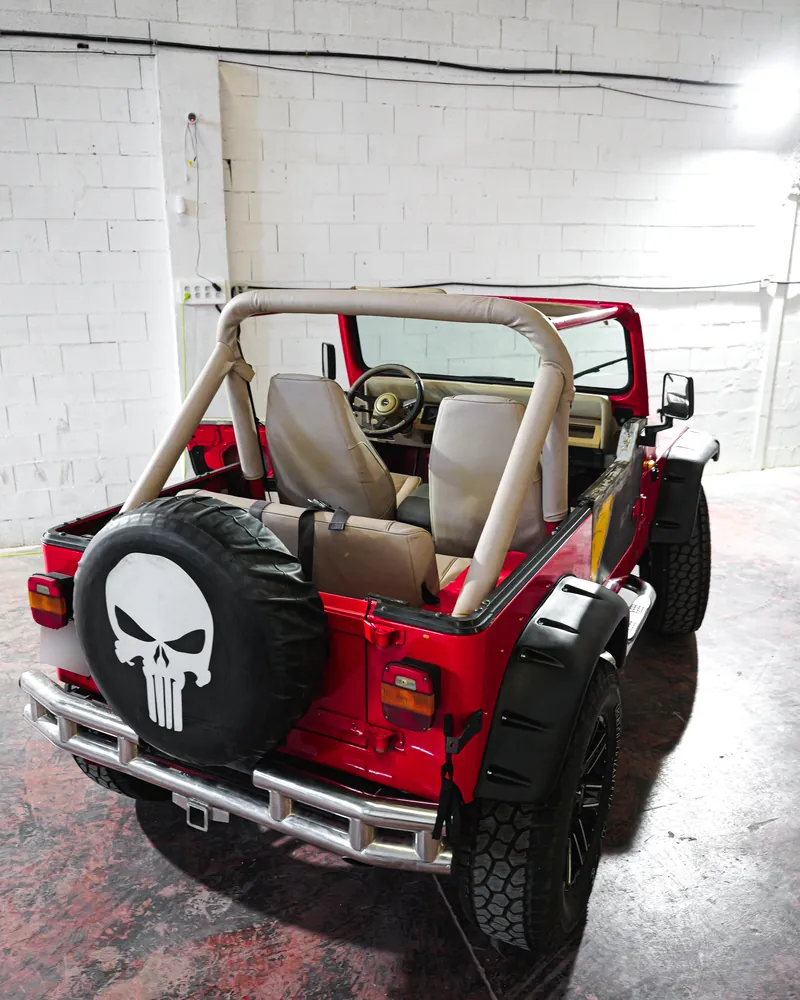 Jeep Wrangler YJ: restauración completa y tapizado a medida 3 Trasera del Jeep Wrangler YJ rojo antes de la restauración, con rueda de repuesto con calavera