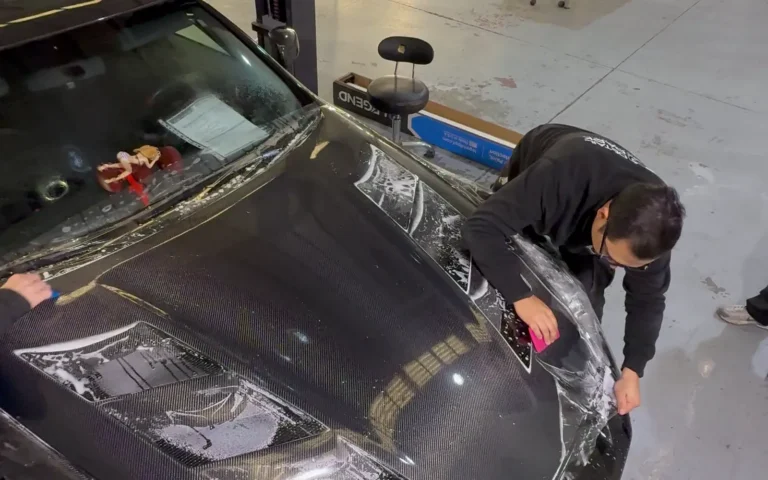 Técnico de Detail Park instalando PPF STEK sobre el capó de fibra de carbono de un Nissan 370Z Nismo negro