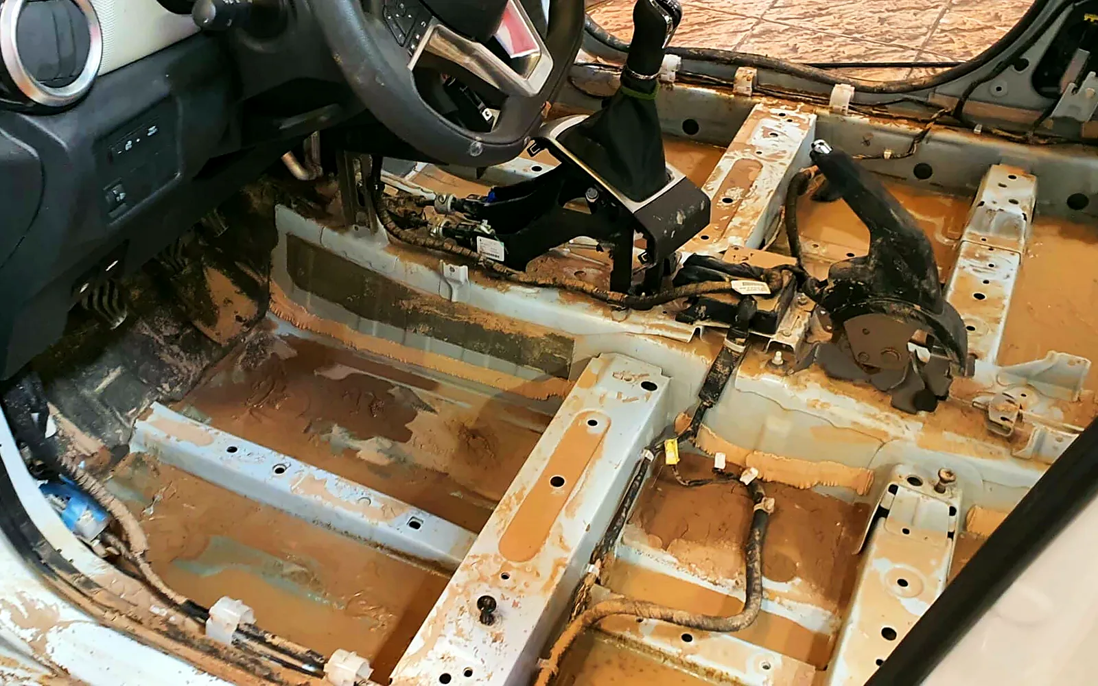 Limpieza de un coche inundado: así recuperamos este Nissan Micra 1 Suelo del Nissan Micra inundado sin moqueta, con barro seco antes de la limpieza
