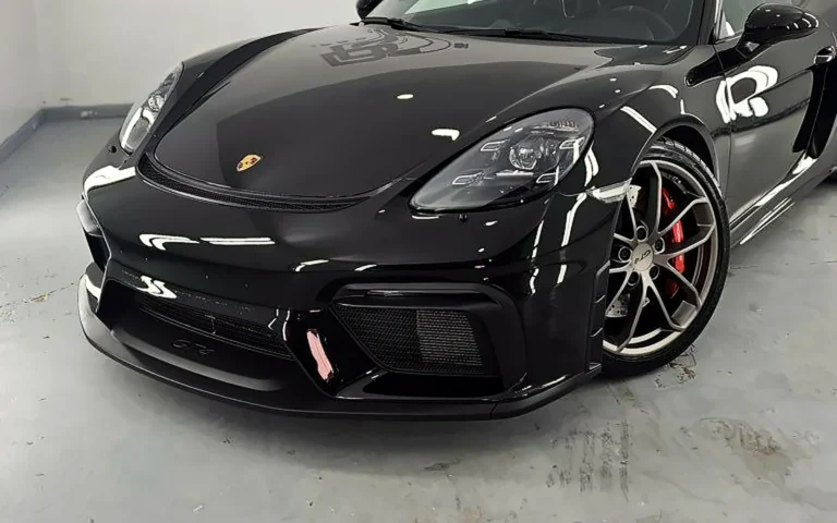Protección cerámica Porsche GT4: frontal del 718 Cayman negro con la pinza roja en la cabina