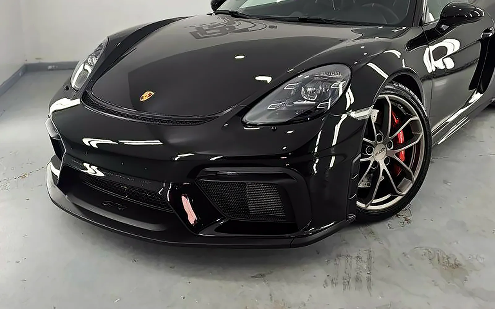 Protección cerámica Porsche GT4: corrección y coating Gtechniq 1 Protección cerámica Porsche GT4: frontal del 718 Cayman negro con la pinza roja en la cabina