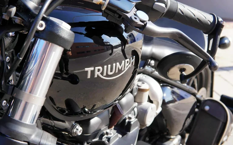 Depósito negro de la moto Triumph con el logotipo y reflejos limpios tras el pulido