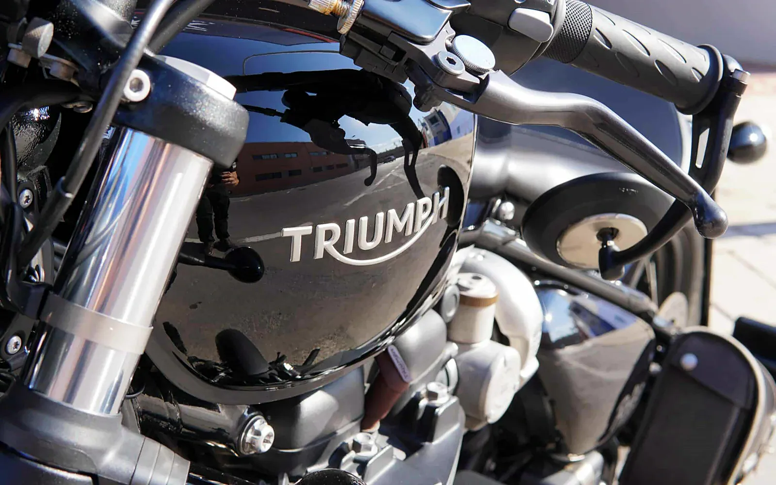 Pulido de moto Triumph: corrección y protección cerámica 1 Depósito negro de la moto Triumph con el logotipo y reflejos limpios tras el pulido