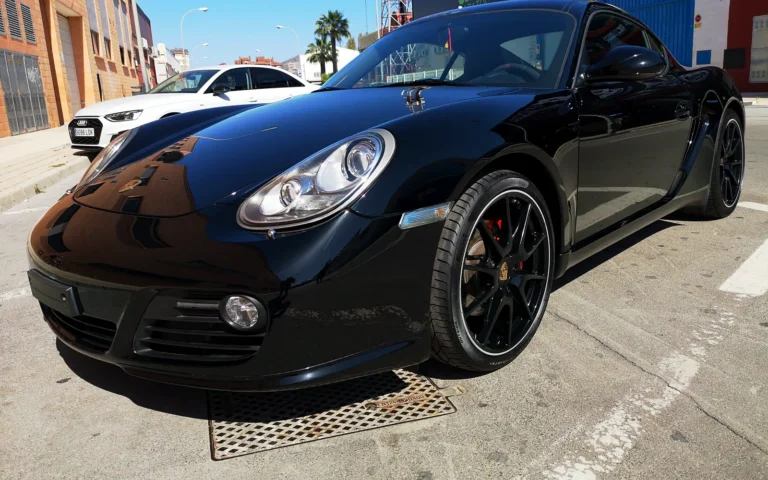 Pulido del Porsche Cayman S negro: tres cuartos delantero con llantas negras y pinzas rojas