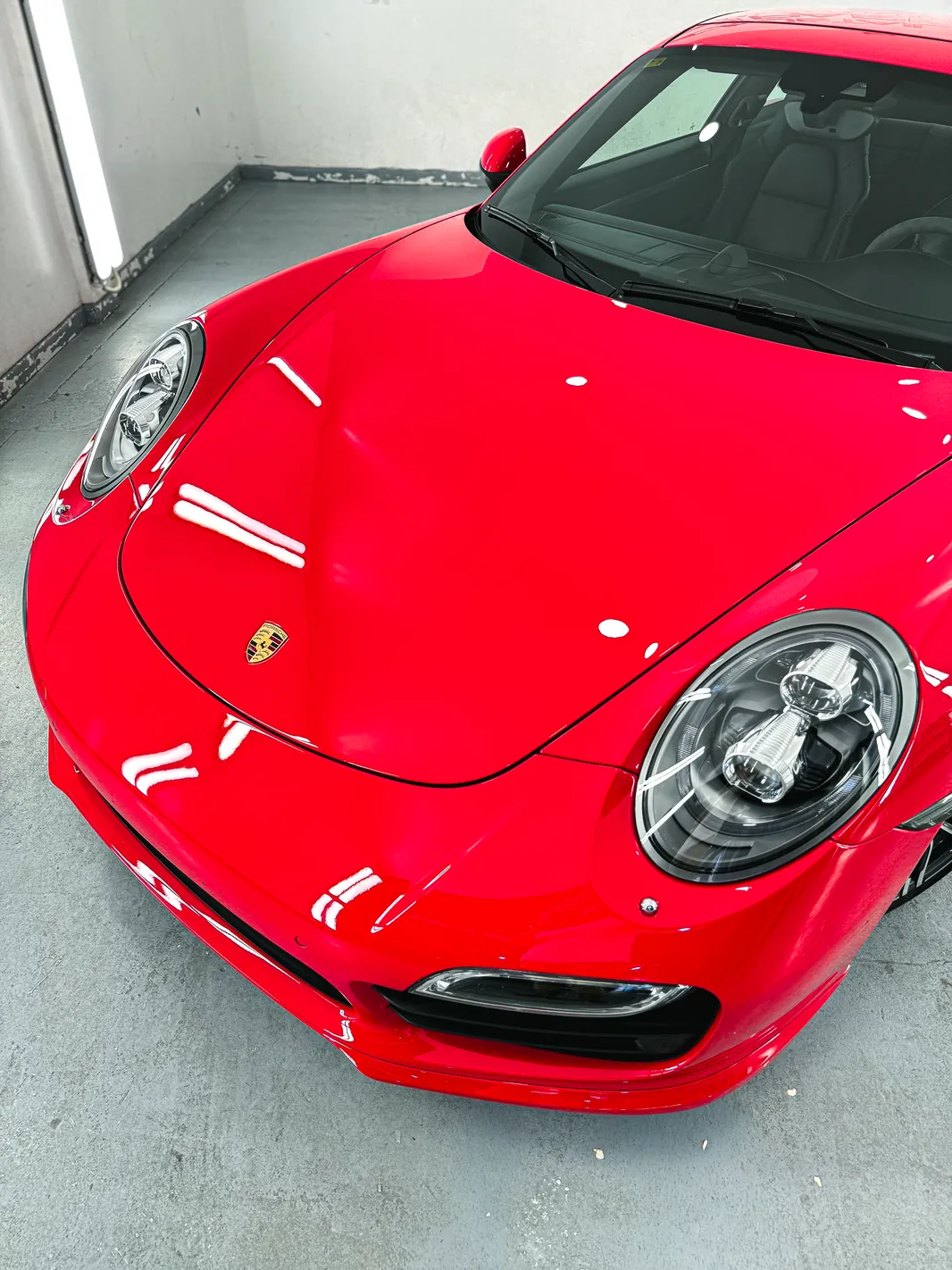 Porsche 911 Turbo (991): tratamiento cerámico Gtechniq de doble capa 5 Reflejos nítidos en el capó y el faro del Porsche 911 Turbo tras el pulido y el cerámico