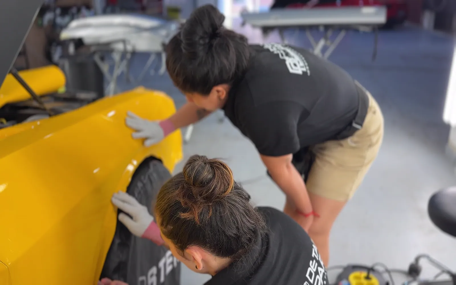 Yajaira y Dayana: formación completa en car wrapping y detailing para trabajar en Estados Unidos 1 Yajaira y Dayana aplicando vinilo amarillo en una aleta durante la formación de car wrapping en Detail Park, Alicante